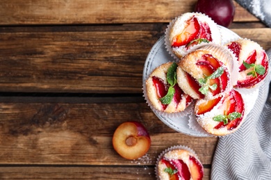 Delicious sweet cupcakes with plums on table, flat lay. Space for text