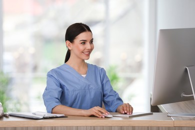 Receptionist working with computer at countertop in hospital