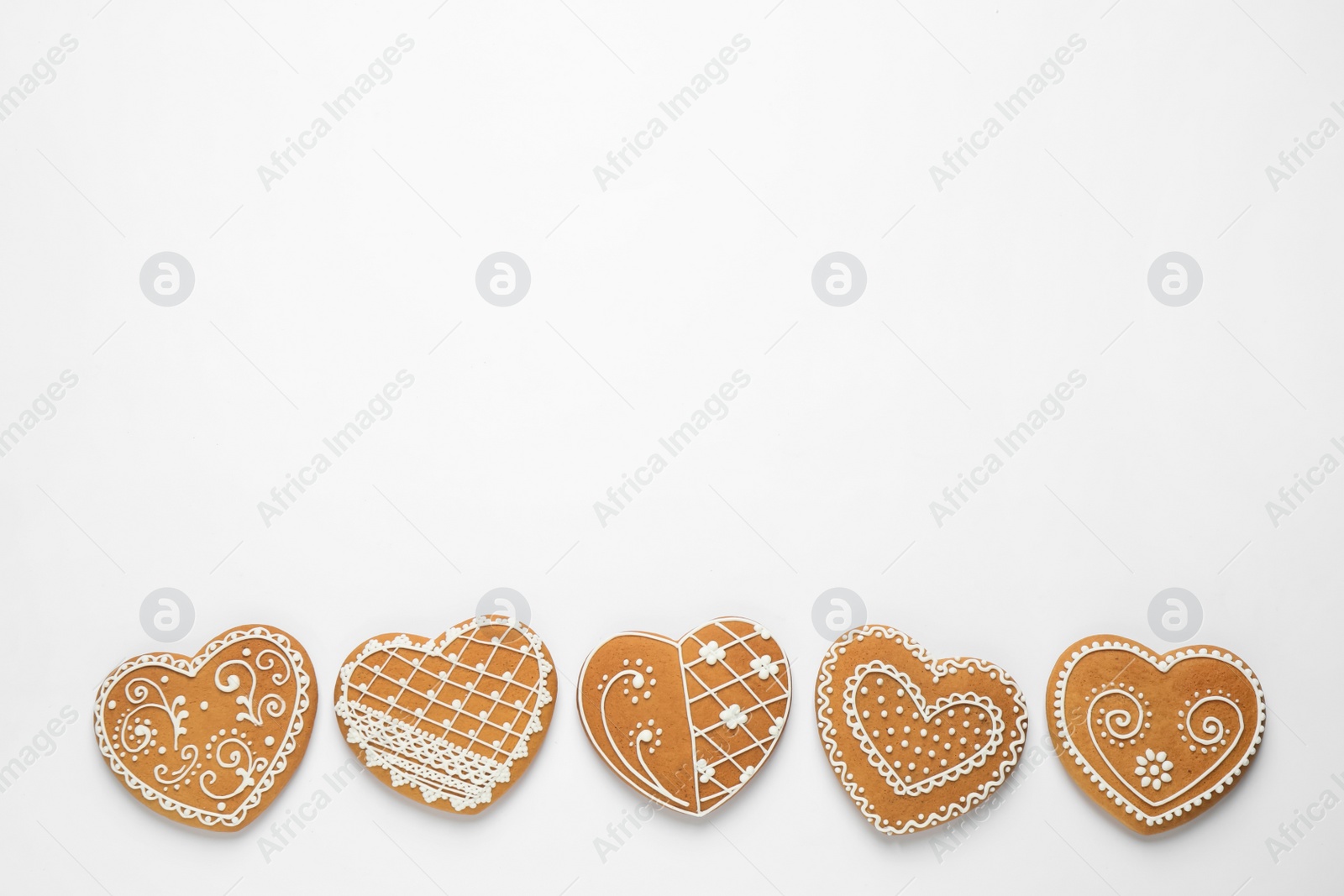Photo of Gingerbread hearts decorated with icing on white background, flat lay. Space for text