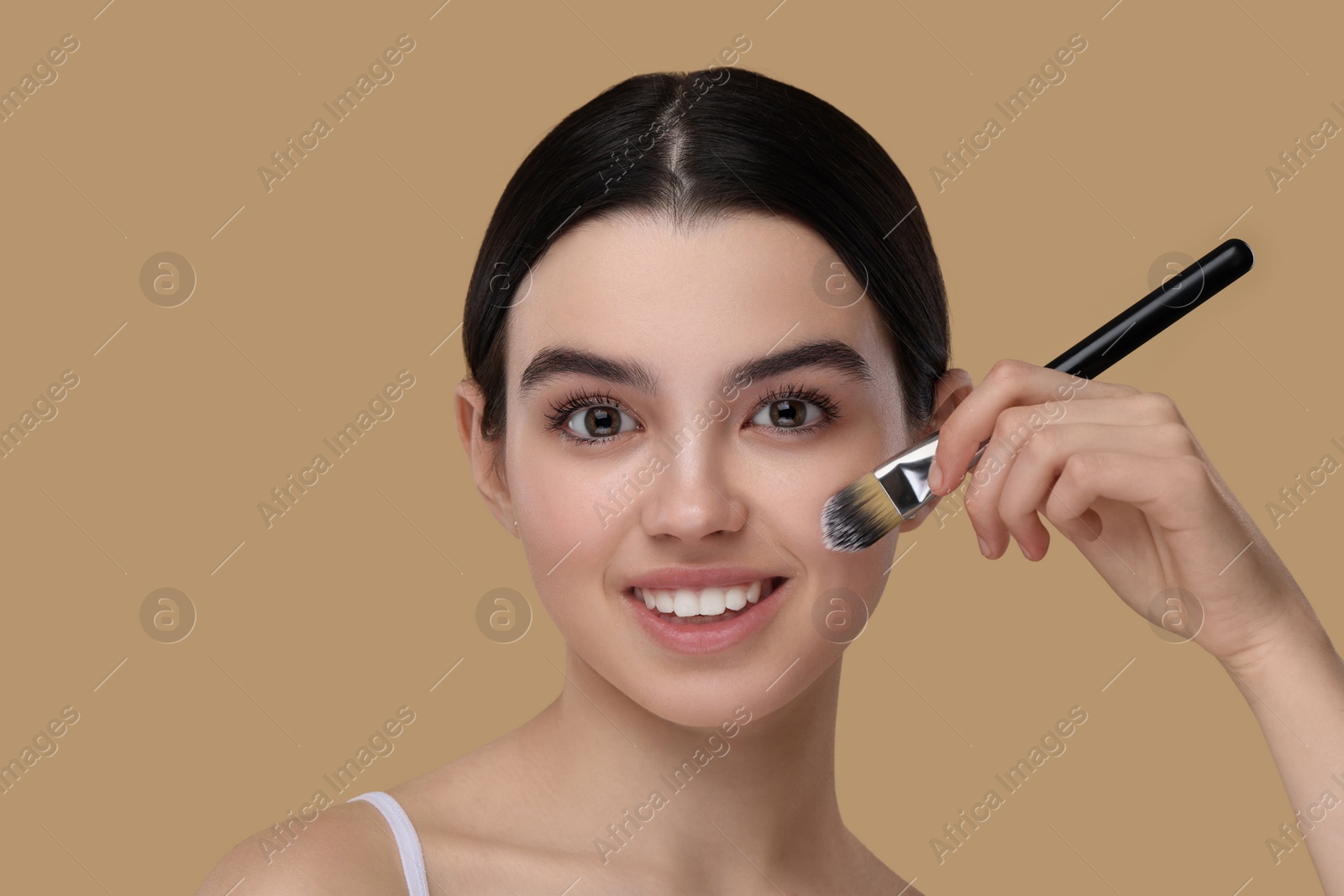 Photo of Teenage girl with makeup brush on beige background