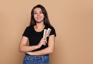 Photo of Happy professional hairdresser with combs against pale orange background. Space for text