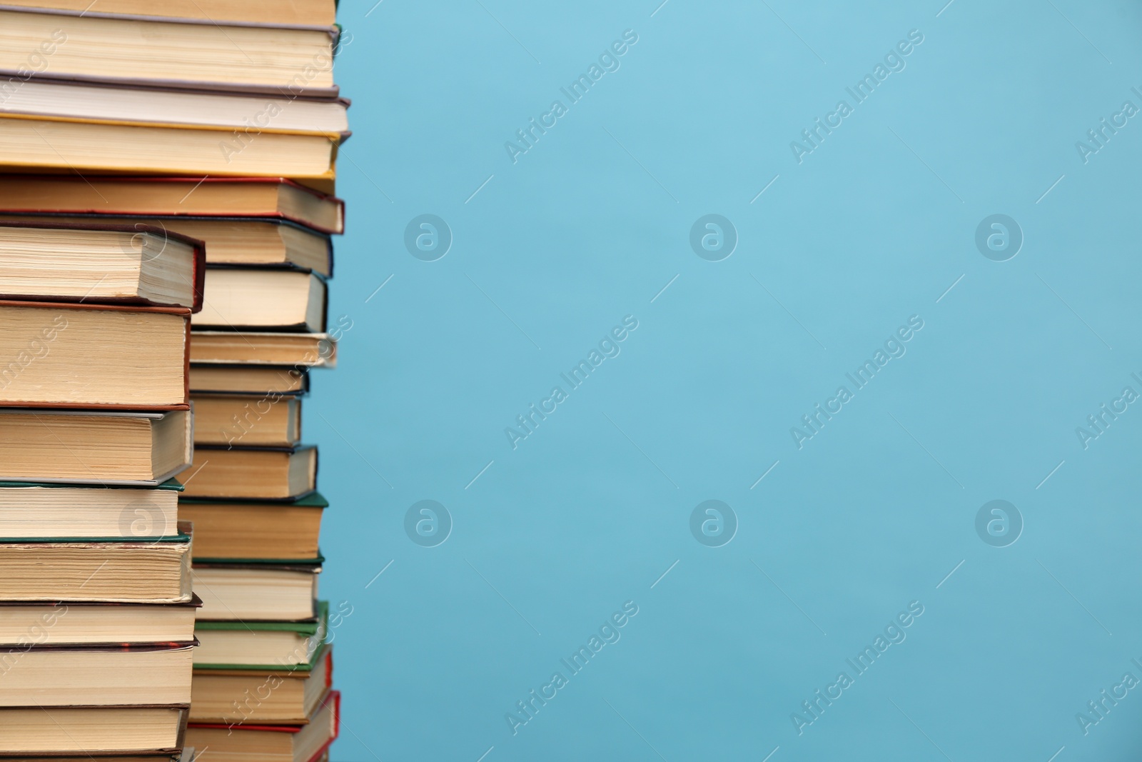 Photo of Many hardcover books on turquoise background, space for text. Library material