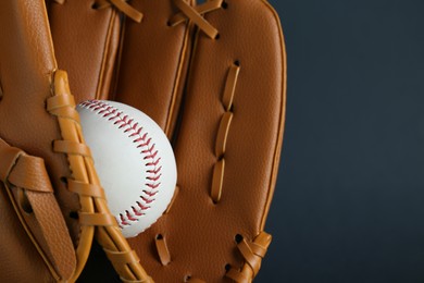 Photo of Catcher's mitt and baseball ball on dark background, closeup with space for text. Sports game