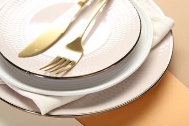 Photo of Ceramic plates, cutlery and napkin on color background, closeup