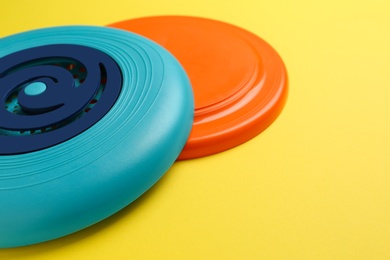 Photo of Plastic frisbee disks on yellow background, closeup