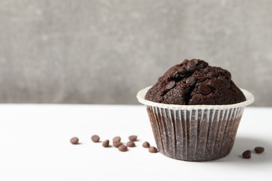 Tasty chocolate muffin on white table, space for text