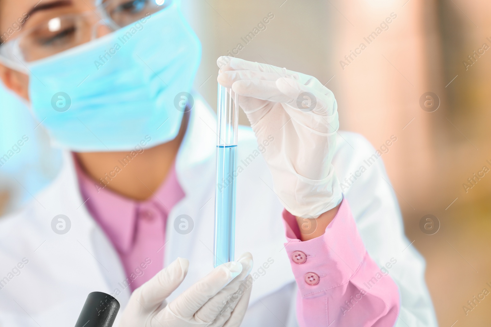 Photo of Young scientist holding test tube with sample on blurred background, closeup. Laboratory analysis