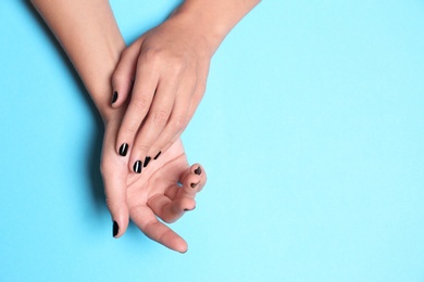 Photo of Woman showing black manicure on color background, top view with space for text. Nail polish trends