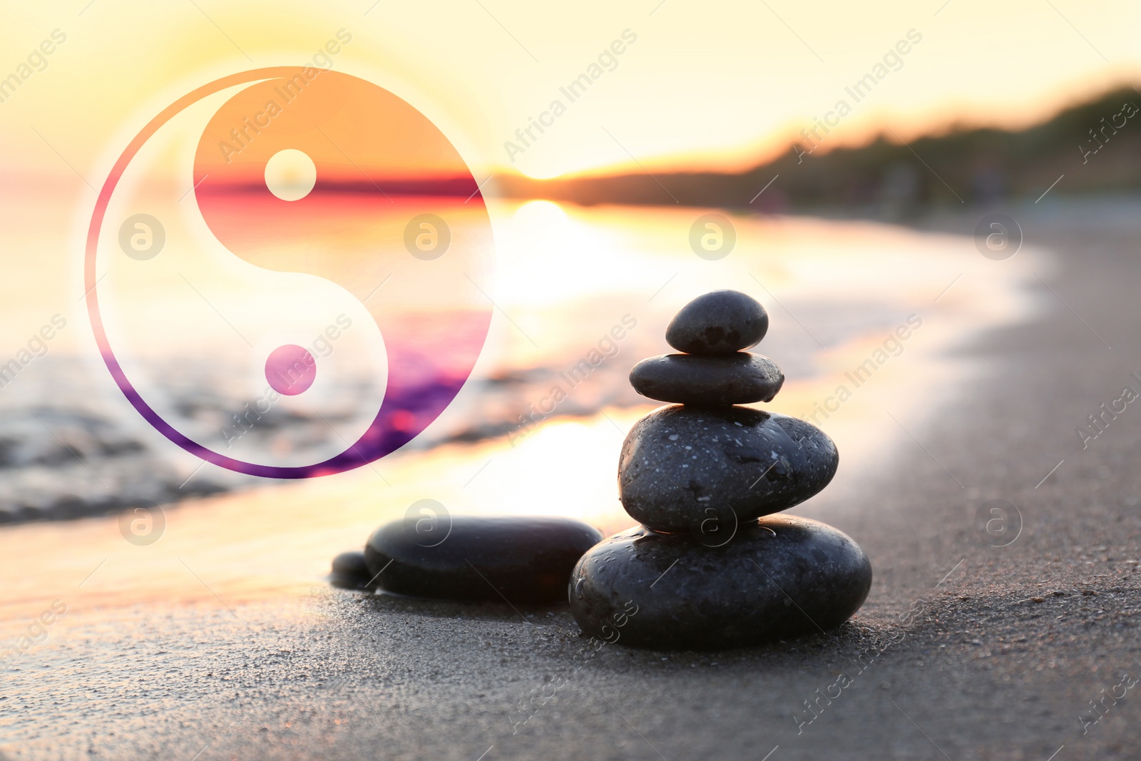 Image of Stack of stones on sandy beach and Ying Yang symbol. Feng Shui philosophy 