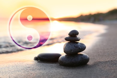 Image of Stack of stones on sandy beach and Ying Yang symbol. Feng Shui philosophy 