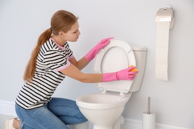 Woman cleaning toilet bowl in bathroom