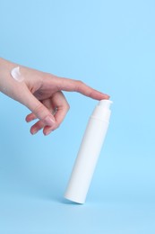 Woman with cream on light blue background, closeup