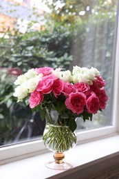 Vase with beautiful bouquet of roses on windowsill indoors