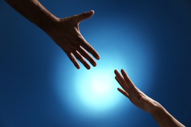 Photo of Man reaching for woman's hand on color background, closeup. Help and support concept