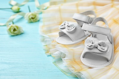 Pair of cute baby sandals and clothes on table