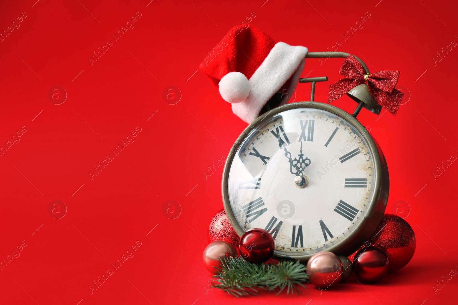 Photo of Alarm clock and festive decor on red background, space for text. New Year countdown