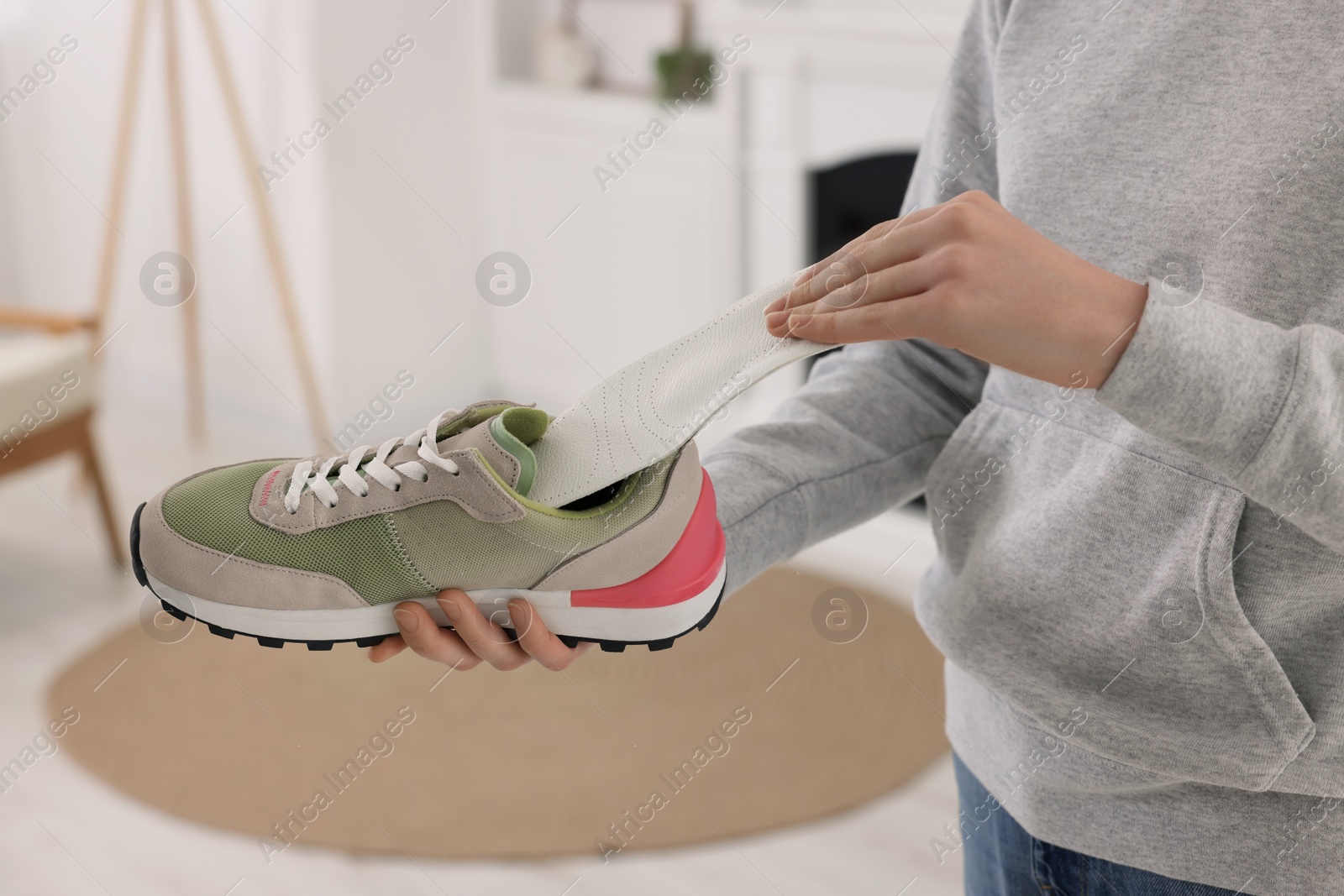 Photo of Woman putting orthopedic insole into shoe at home, closeup. Foot care
