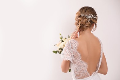 Photo of Young bride with elegant hairstyle holding wedding bouquet on white background, back view