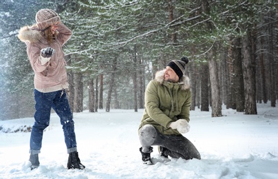 Happy couple playing snowballs in winter forest