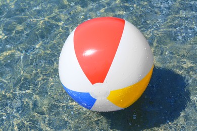 Colorful beach ball floating in sea on sunny day