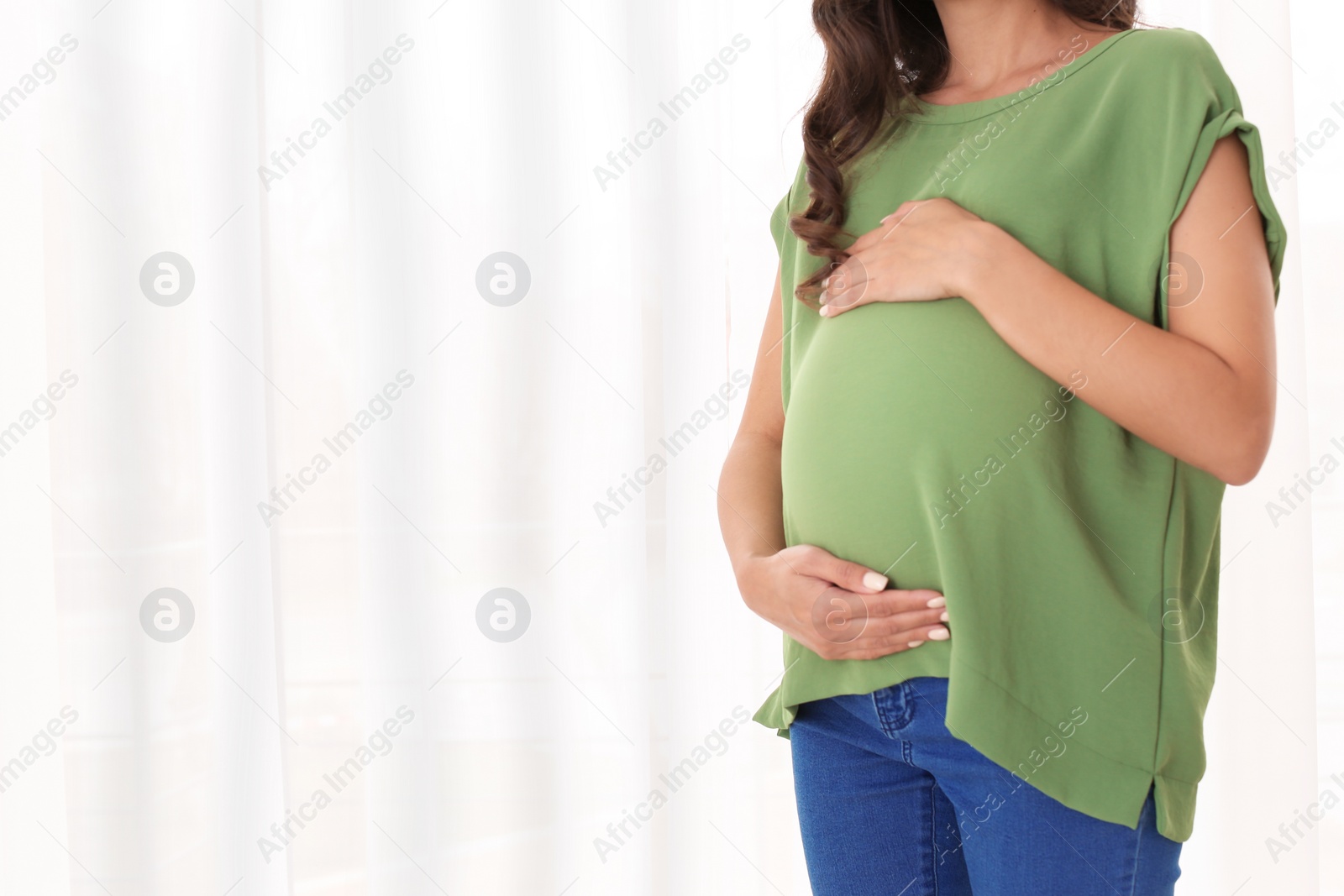 Photo of Beautiful pregnant woman near window at home