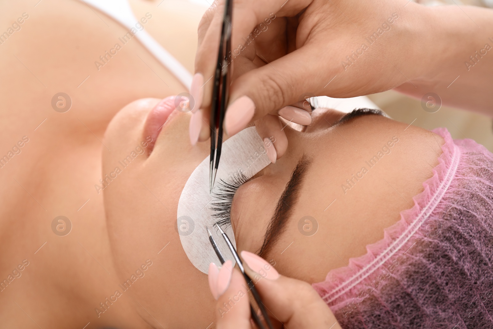 Photo of Young woman undergoing eyelash extensions procedure, closeup