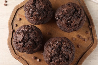 Delicious chocolate muffins on white wooden table, top view