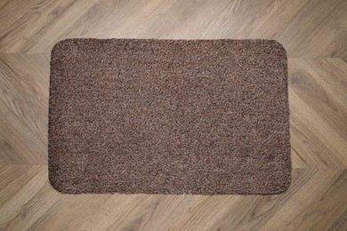 Photo of Stylish door mat on wooden floor, top view