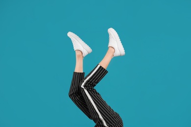 Woman in stylish sport shoes on light blue background