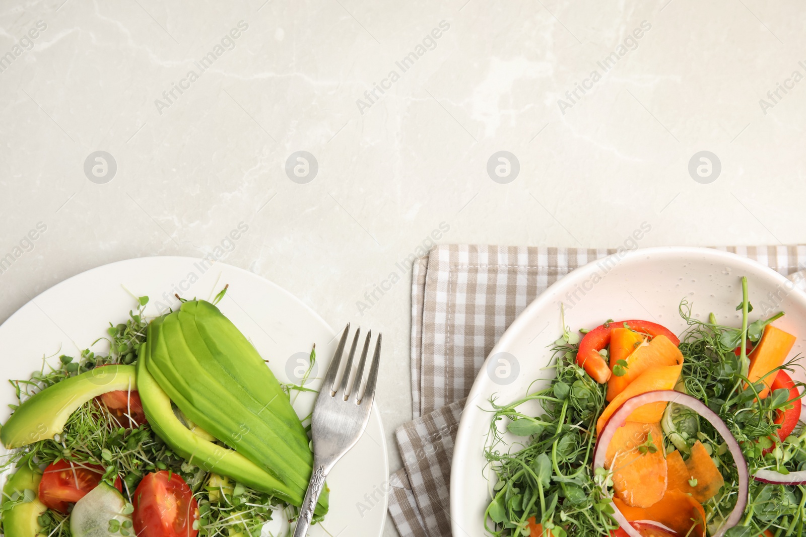 Photo of Delicious vegetable salads with avocado and microgreen served on light table, flat lay. Space for text