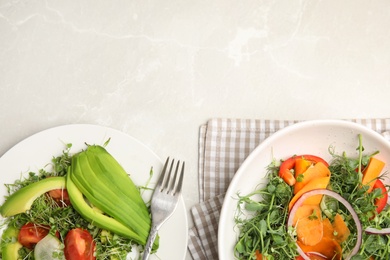 Delicious vegetable salads with avocado and microgreen served on light table, flat lay. Space for text