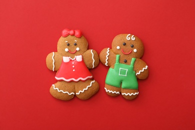 Photo of Christmas human shaped gingerbread cookies on red background, flat lay