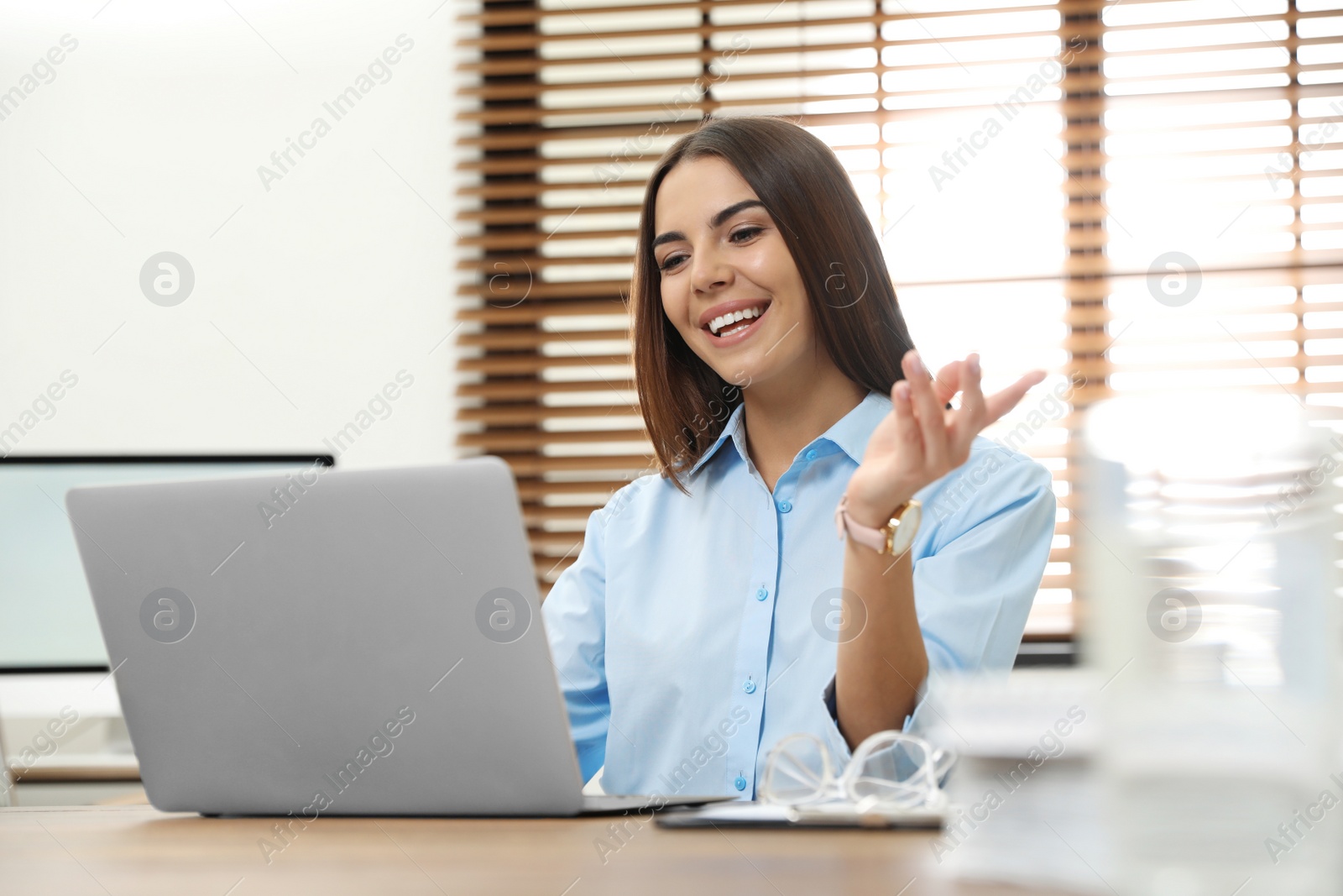 Photo of Young woman using video chat on laptop in home office