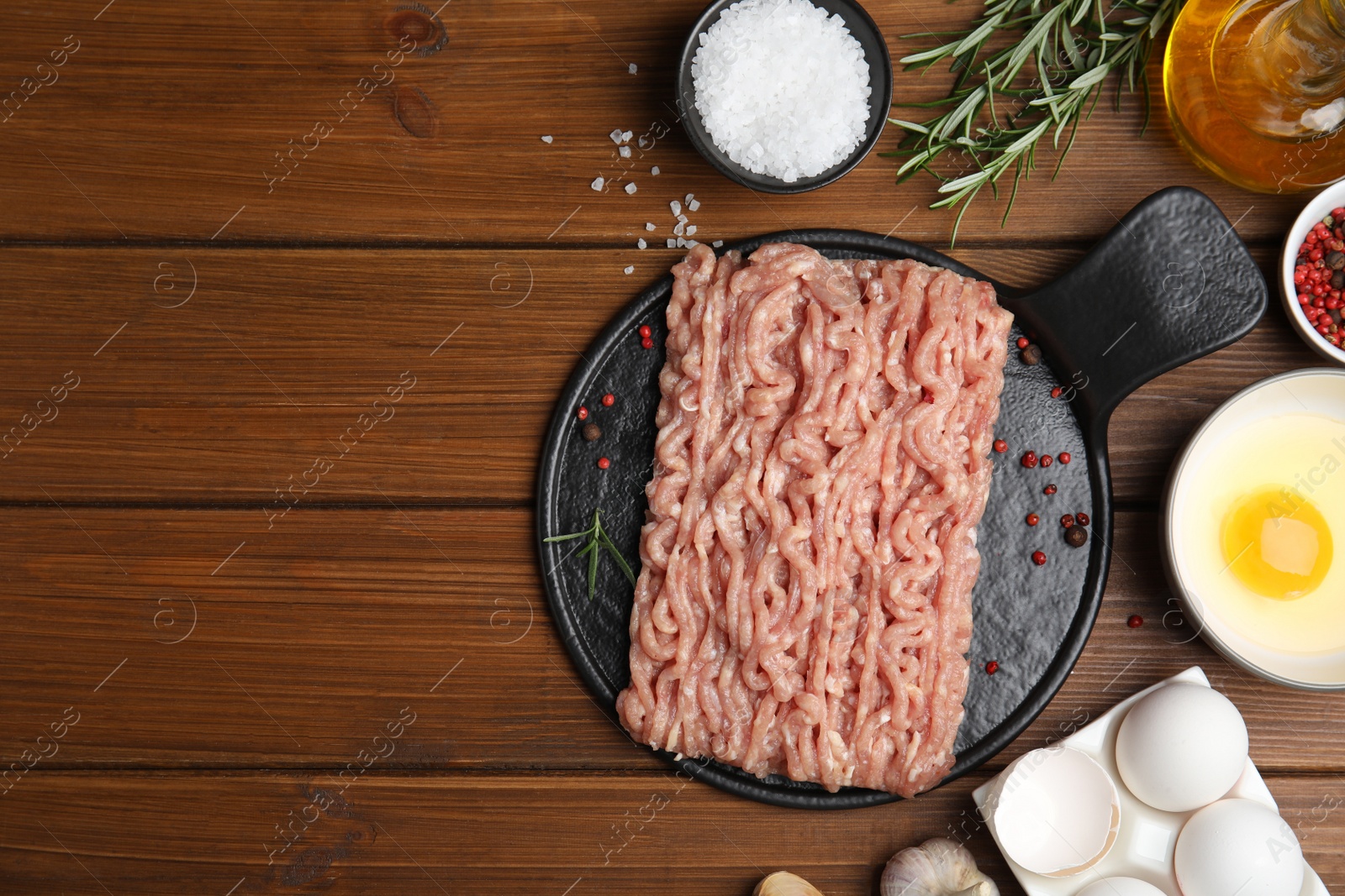 Photo of Raw chicken minced meat and ingredients on wooden table, flat lay. Space for text