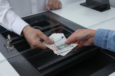 Photo of Woman giving money to cashier in bank, closeup. Currency exchange