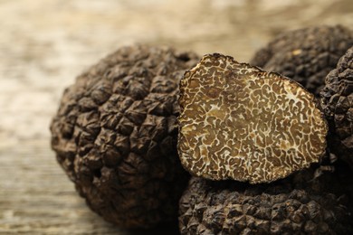 Photo of Heap of whole and cut black truffles on table, closeup