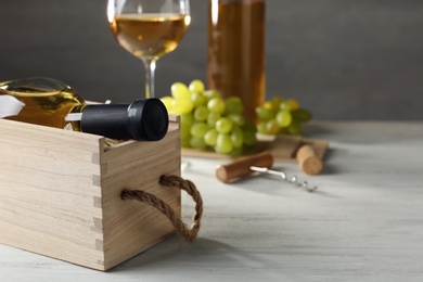 Photo of Wooden crate with bottle of wine on white table