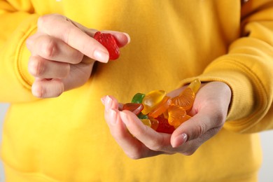Photo of Woman holding handful with delicious gummy fruit shaped candies, closeup