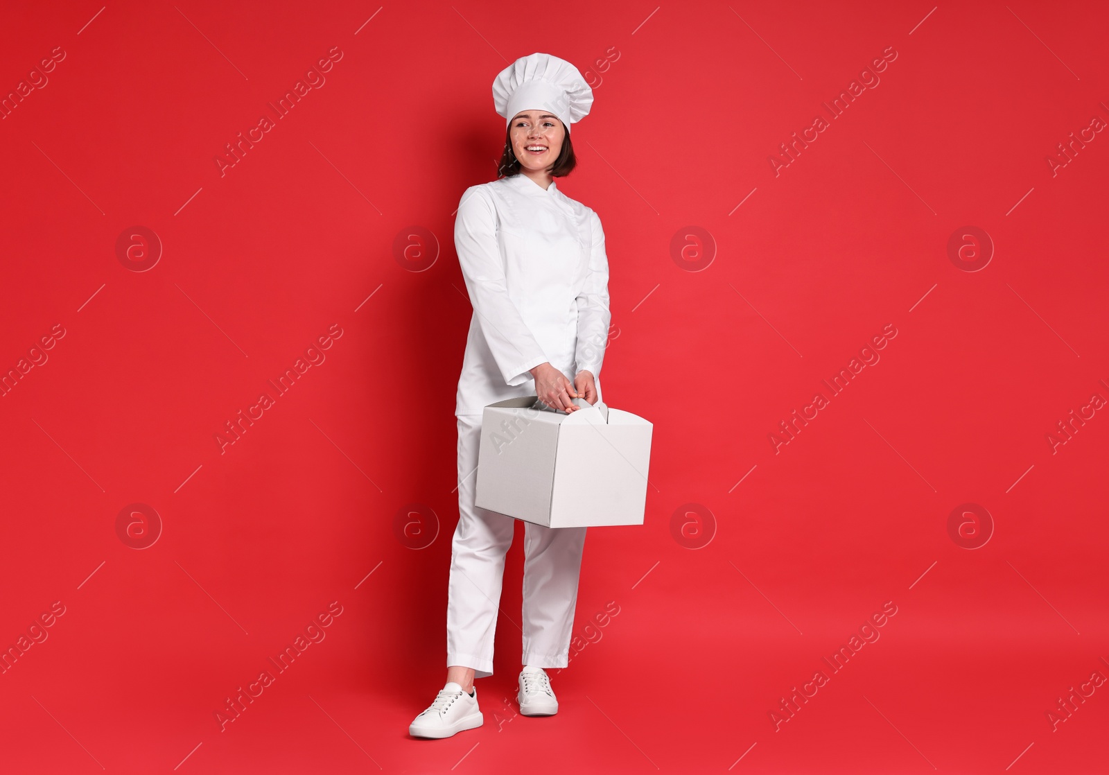 Photo of Happy confectioner with cake box on red background