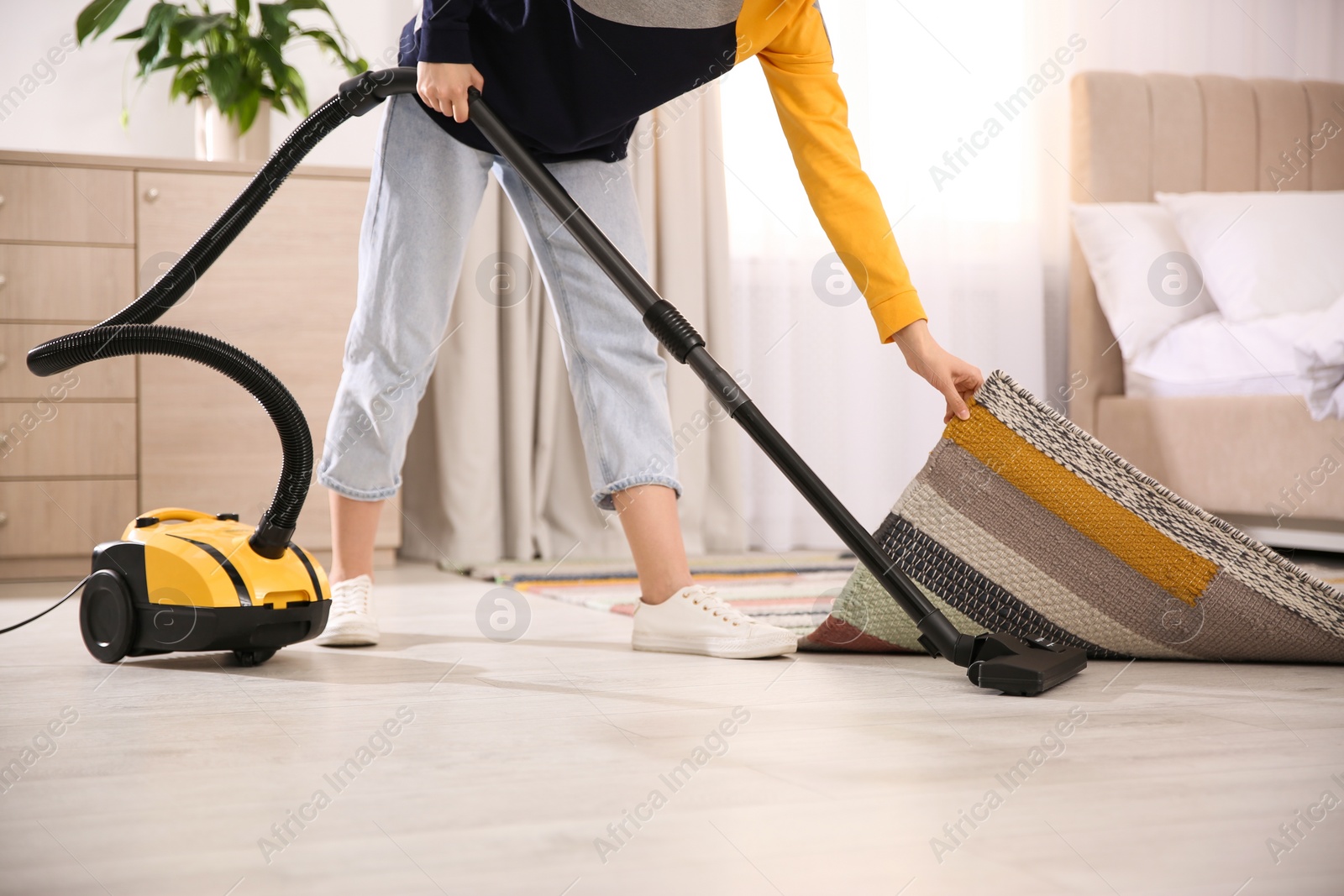 Photo of Young woman using vacuum cleaner at home, closeup