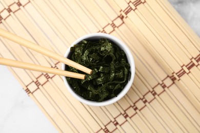 Photo of Chopped nori sheets with chopsticks on white marble table, top view