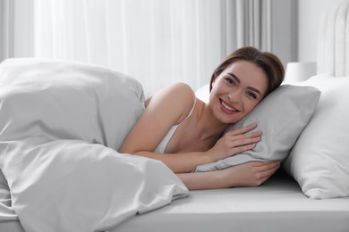Photo of Young woman lying in comfortable bed with silky linens