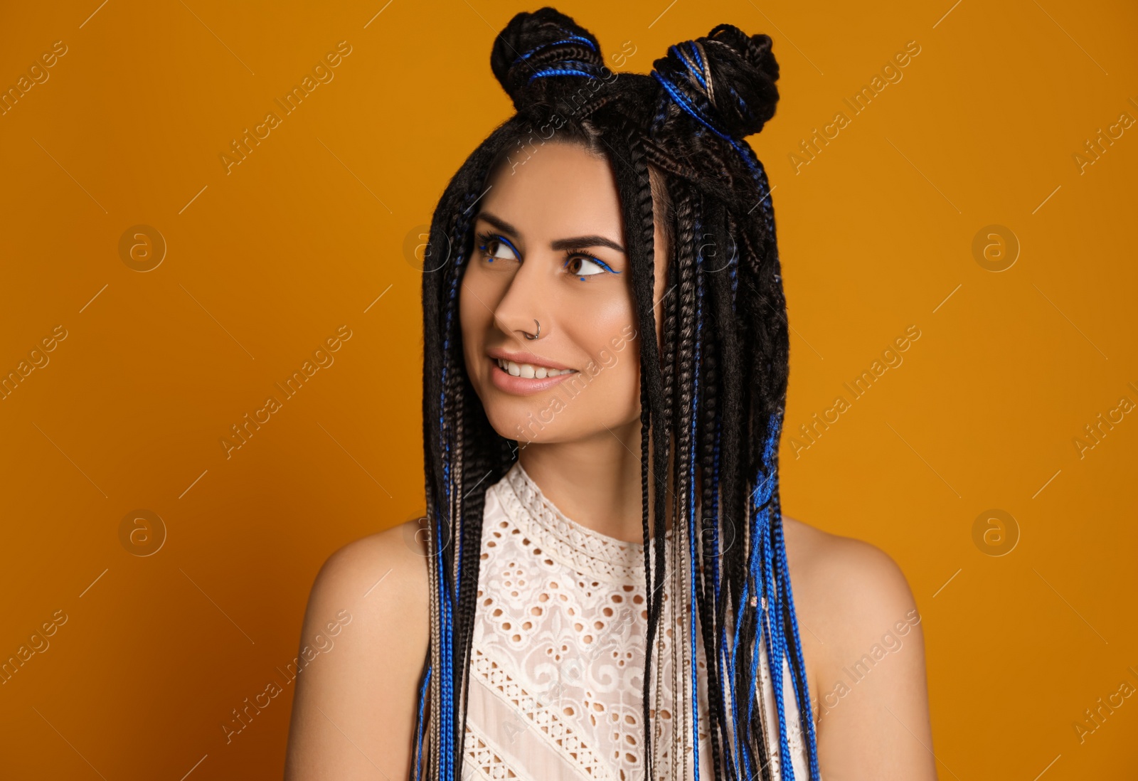 Photo of Beautiful young woman with nose piercing and dreadlocks on yellow background