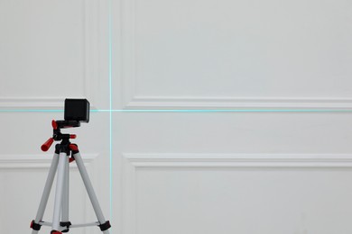 Photo of Cross line laser level on tripod in front of white wall