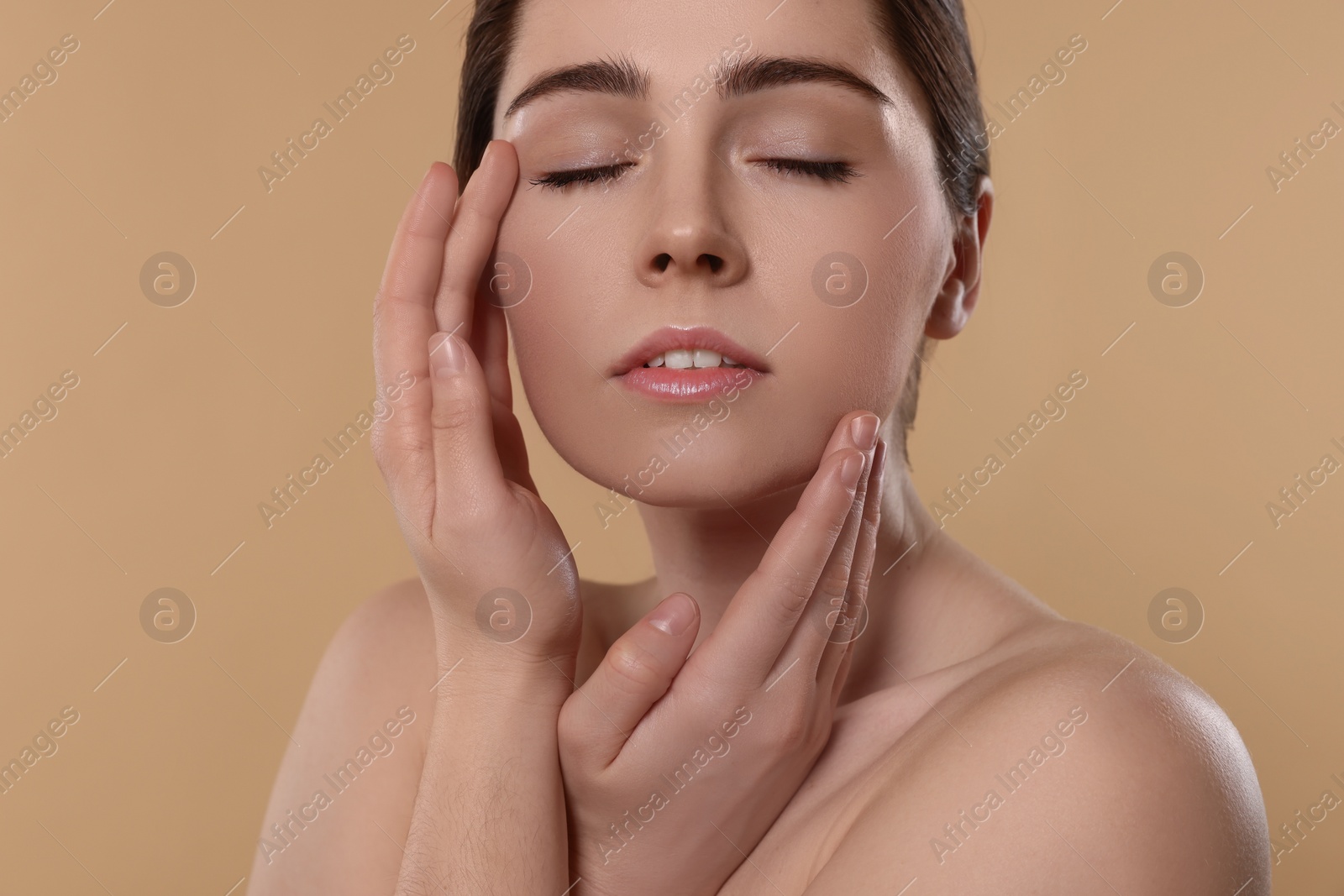 Photo of Young woman massaging her face on beige background