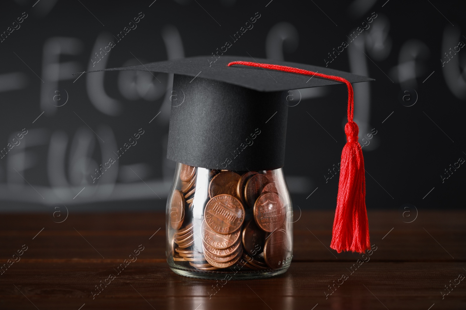 Photo of Scholarship concept. Graduation cap and jar with coins on wooden table