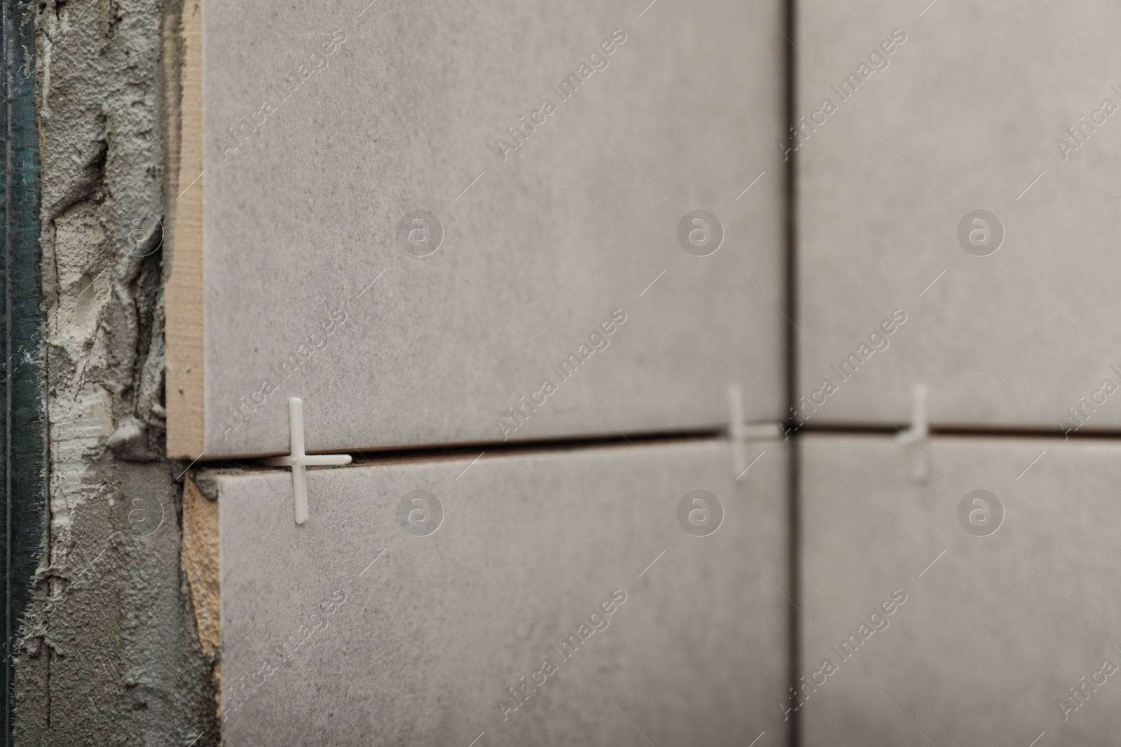 Photo of Stylish tiles with spacers on wall in room