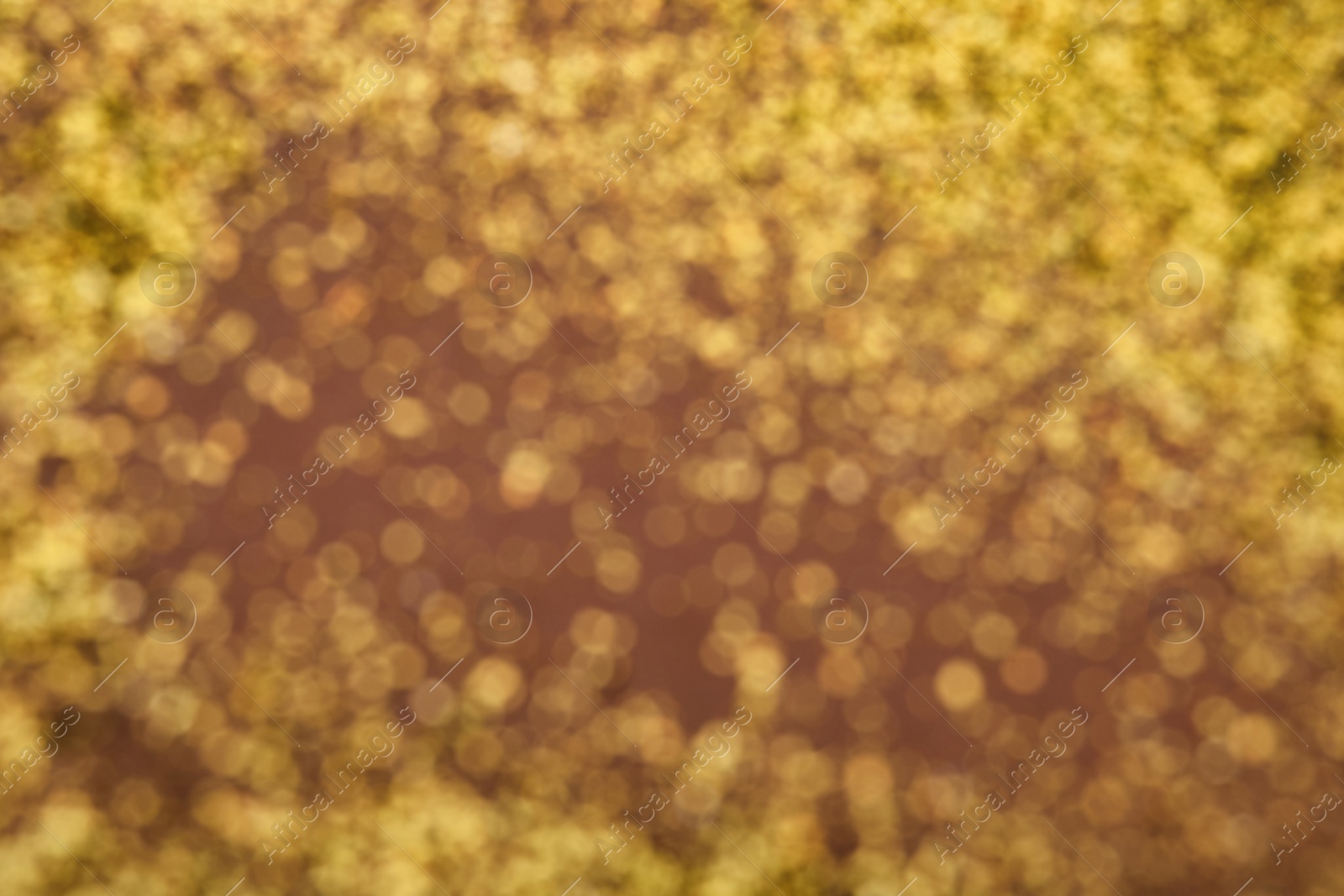 Photo of Blurred view of golden glitter on dusty rose background. Bokeh effect