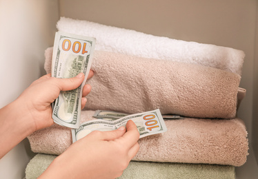 Woman hiding money between towels, closeup. Financial savings
