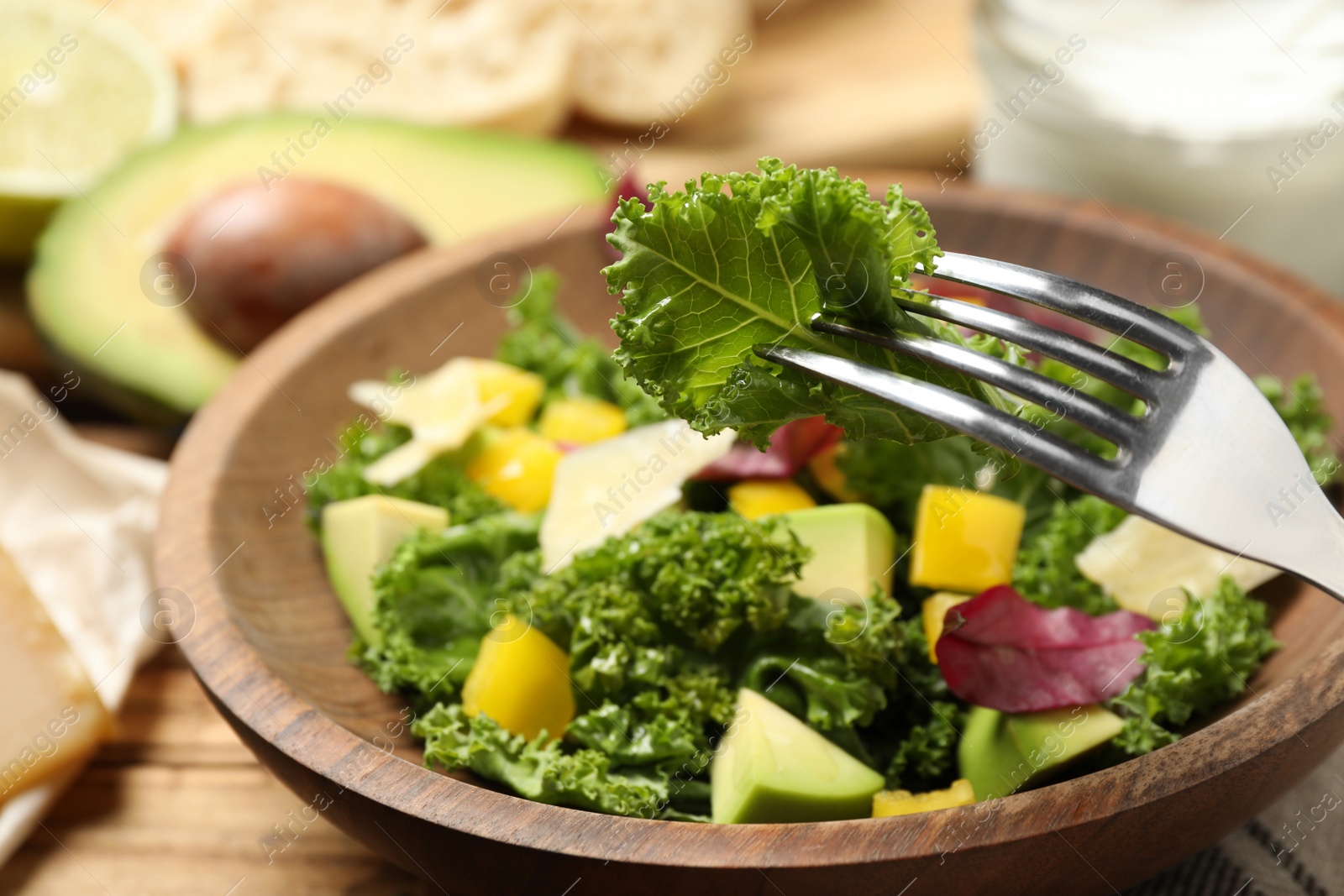 Photo of Delicious kale salad in wooden bowl, closeup